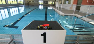 Foto des Sprungbocks mit der Nummer "1" im SimmBad. Auf dem Bock liegt eine gelb-orange Taucherbrille, im Hintergrund ist das Wasser zu sehen.